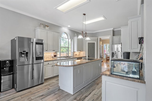 kitchen with white cabinetry, crown molding, a center island, stainless steel fridge, and backsplash