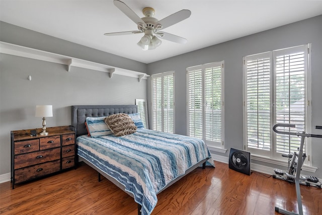 bedroom with ceiling fan, wood finished floors, and baseboards