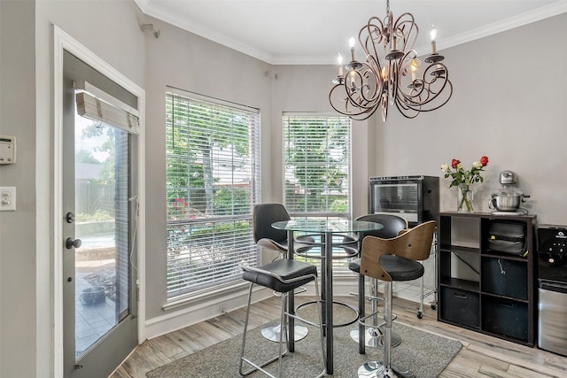 dining area featuring wood finished floors, an inviting chandelier, and crown molding