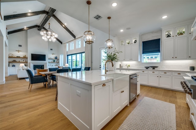kitchen featuring high vaulted ceiling, appliances with stainless steel finishes, white cabinets, and a center island with sink