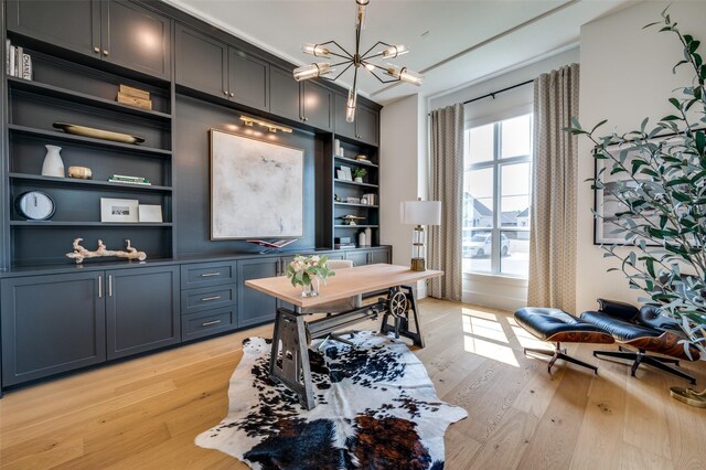 home office featuring light wood-type flooring, a notable chandelier, and built in shelves