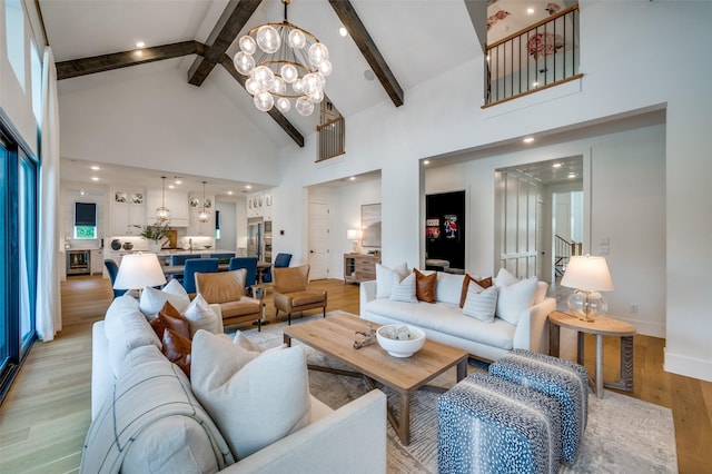 living area featuring beamed ceiling, light wood-style floors, baseboards, high vaulted ceiling, and a notable chandelier