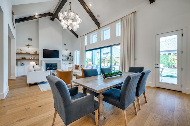 dining space featuring beamed ceiling, light wood-style floors, built in shelves, a notable chandelier, and high vaulted ceiling