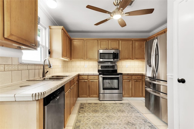 kitchen with tile counters, stainless steel appliances, light tile patterned floors, and a sink