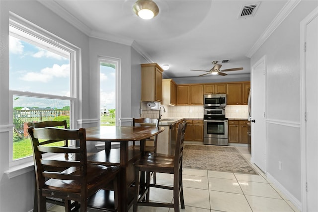 dining space featuring light tile patterned flooring, visible vents, ceiling fan, and crown molding