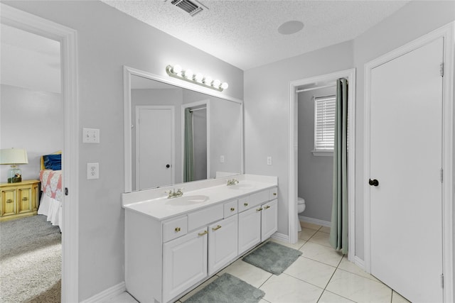 ensuite bathroom with a sink, ensuite bath, toilet, visible vents, and a textured ceiling