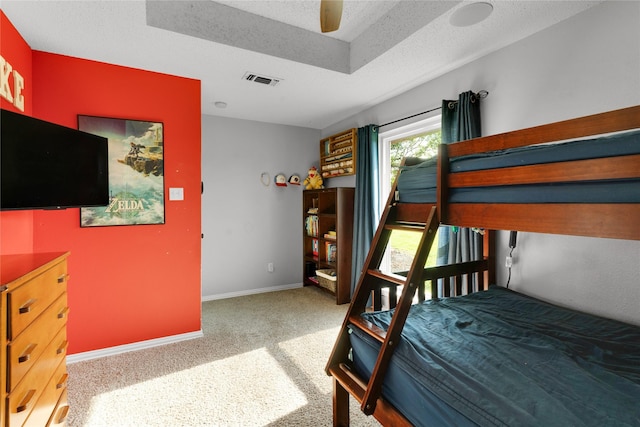 carpeted bedroom featuring baseboards, visible vents, a raised ceiling, and a ceiling fan