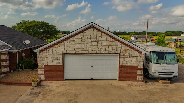 exterior space with a detached garage, an outbuilding, and stone siding