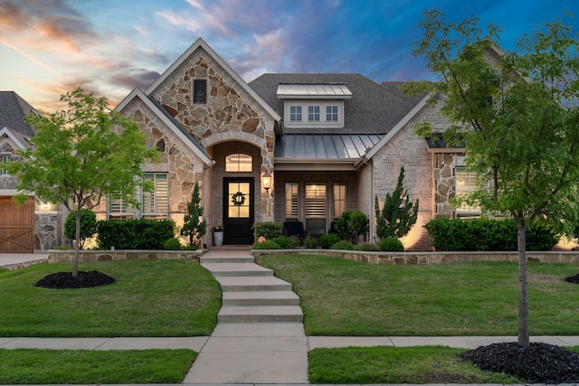 view of front of property with metal roof, a standing seam roof, a yard, and stone siding
