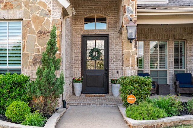 entrance to property featuring roof with shingles and brick siding