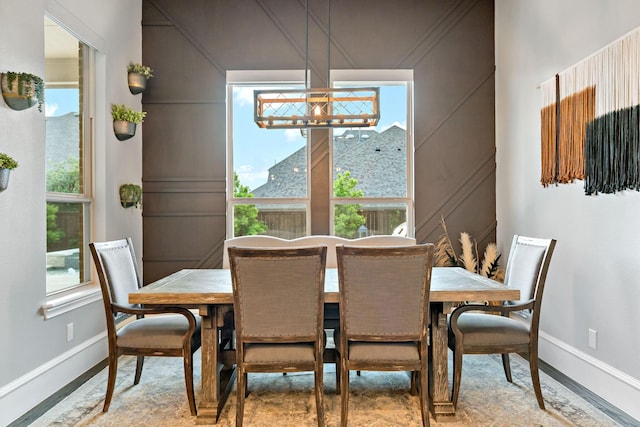 dining room with baseboards, wood finished floors, and a decorative wall