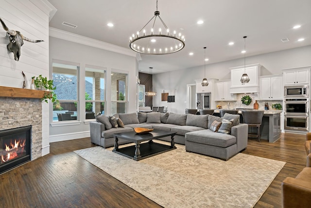 living area featuring recessed lighting, an inviting chandelier, visible vents, a stone fireplace, and ornamental molding