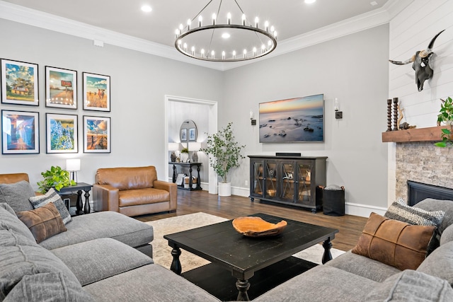 living room featuring wood finished floors, a chandelier, a fireplace, baseboards, and crown molding