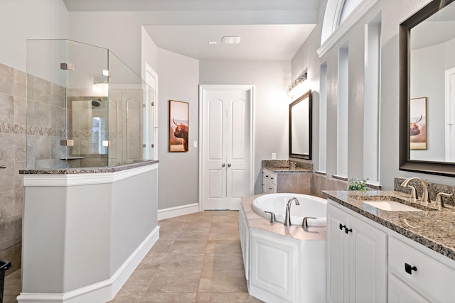 bathroom featuring a sink, a bath, two vanities, baseboards, and walk in shower