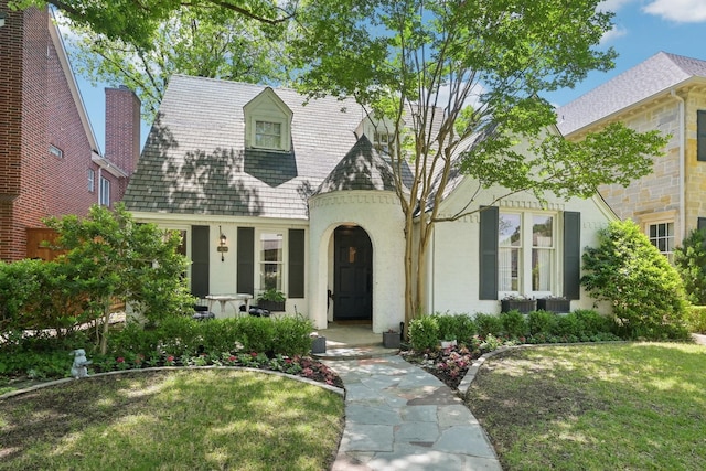 view of front of home with a front yard, stucco siding, and a chimney