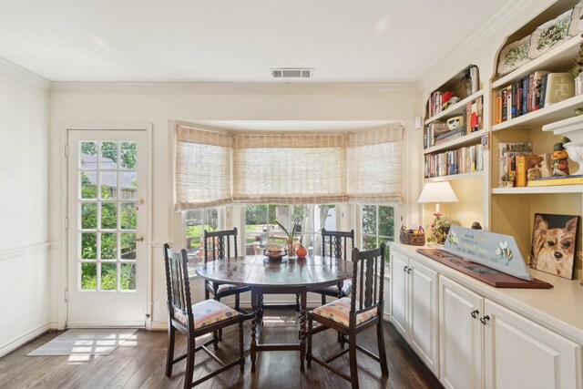 dining room featuring dark wood-type flooring, visible vents, and crown molding