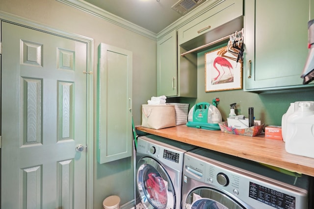clothes washing area featuring visible vents, ornamental molding, washer and clothes dryer, and cabinet space