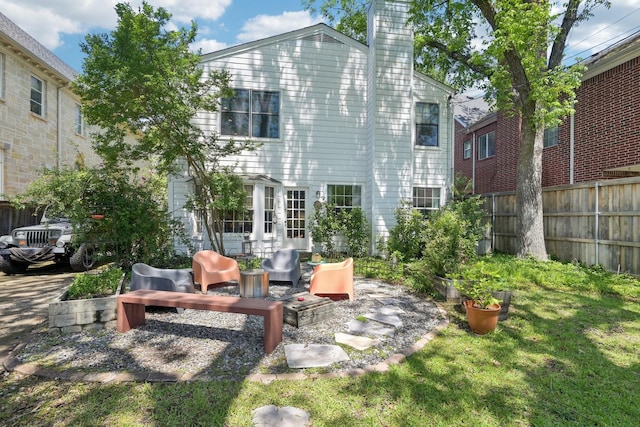 rear view of house featuring fence, a chimney, a lawn, and an outdoor living space
