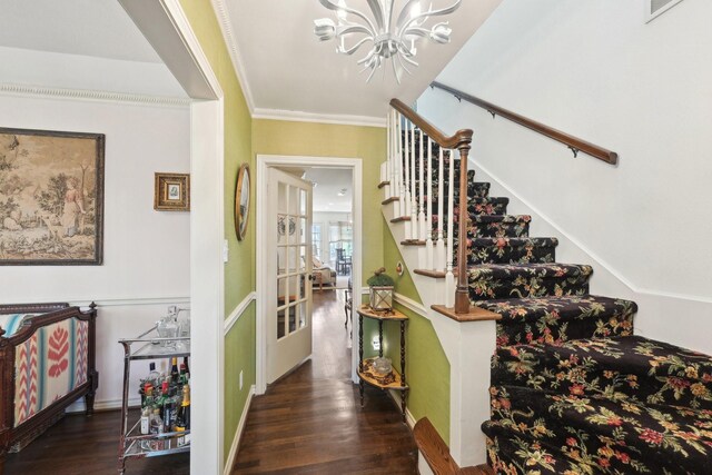 stairway featuring wood finished floors, a chandelier, ornamental molding, baseboards, and visible vents