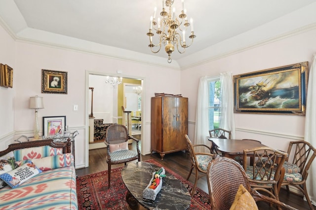 interior space featuring a raised ceiling, a wainscoted wall, a notable chandelier, and dark wood finished floors