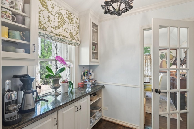 interior space featuring glass insert cabinets, dark stone counters, dark wood-style flooring, white cabinetry, and crown molding