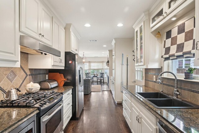 kitchen with stainless steel appliances, under cabinet range hood, a sink, white cabinetry, and visible vents