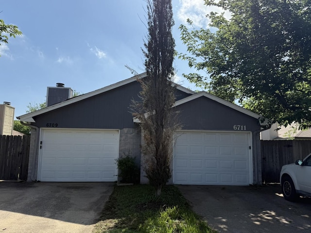 view of front of house featuring a chimney, fence, and a garage