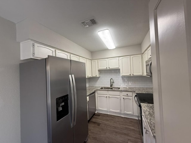 kitchen with a sink, white cabinets, stainless steel appliances, and dark wood-type flooring
