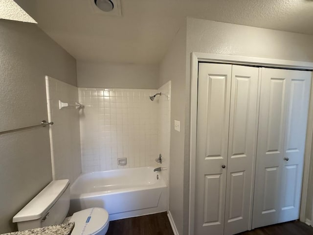 bathroom with wood finished floors, a closet, toilet, a textured wall, and washtub / shower combination