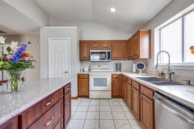 kitchen with lofted ceiling, a textured ceiling, a sink, appliances with stainless steel finishes, and light tile patterned flooring