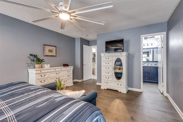 bedroom with ceiling fan, ensuite bath, dark wood-type flooring, baseboards, and a textured ceiling