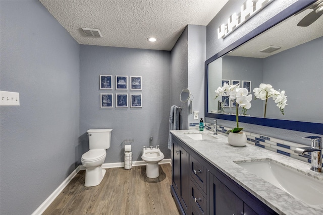 bathroom featuring a bidet, a sink, toilet, visible vents, and wood finished floors