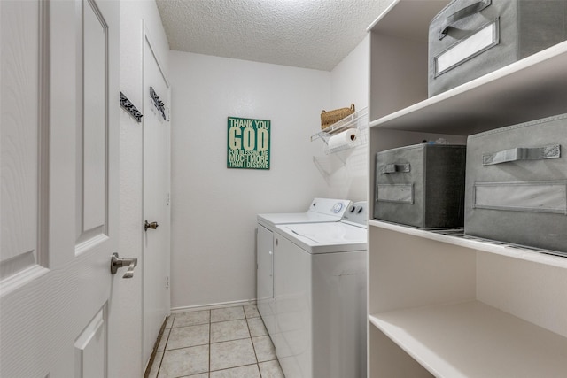 clothes washing area featuring washer and clothes dryer, light tile patterned floors, a textured ceiling, and laundry area
