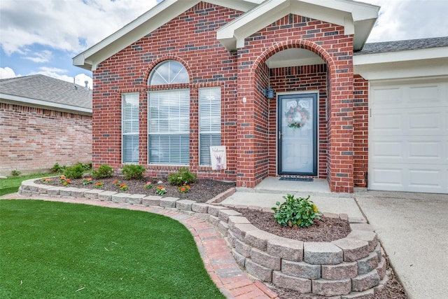 doorway to property featuring driveway, a yard, brick siding, and a garage
