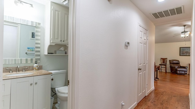 bathroom featuring visible vents, ceiling fan, toilet, wood finished floors, and vanity