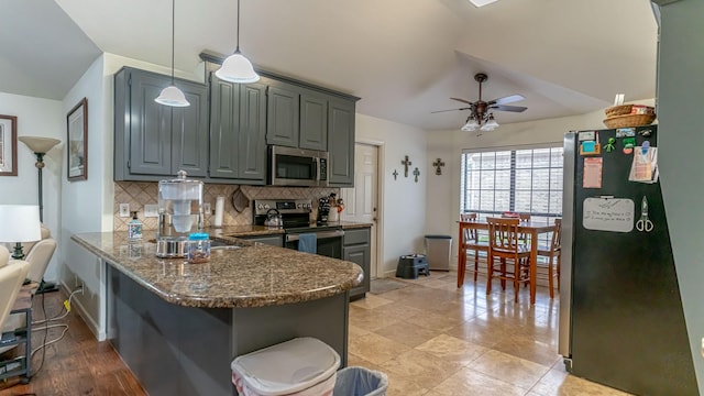 kitchen with dark stone countertops, decorative backsplash, stainless steel appliances, a peninsula, and a ceiling fan