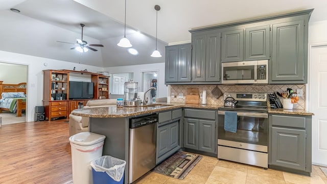 kitchen with appliances with stainless steel finishes, vaulted ceiling, backsplash, gray cabinetry, and a peninsula