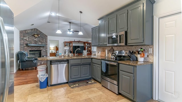 kitchen with stainless steel appliances, open floor plan, vaulted ceiling, a peninsula, and gray cabinets