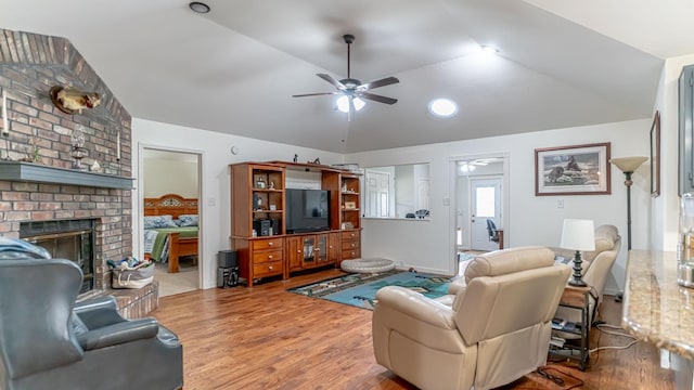 living area with a fireplace, ceiling fan, lofted ceiling, baseboards, and wood finished floors