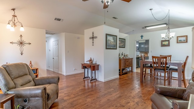 living room with visible vents, wood finished floors, ceiling fan with notable chandelier, and vaulted ceiling