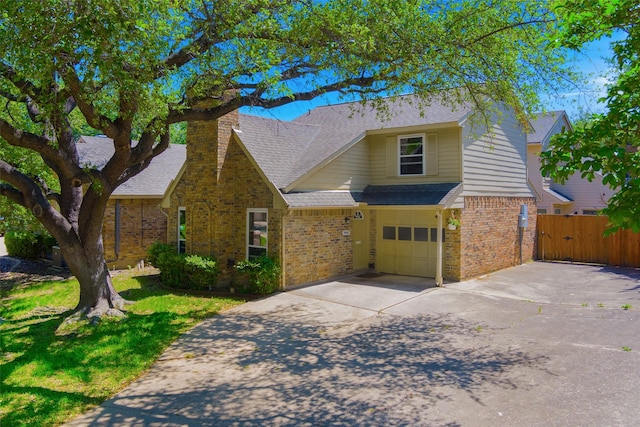 traditional-style home with a garage, a shingled roof, driveway, brick siding, and fence