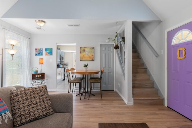 foyer featuring light wood-type flooring, stairs, visible vents, and baseboards
