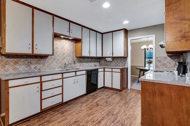 kitchen with stove, wood finished floors, decorative backsplash, black dishwasher, and a sink