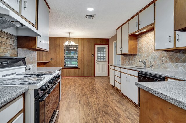 kitchen featuring a sink, under cabinet range hood, white range with gas stovetop, visible vents, and dishwasher