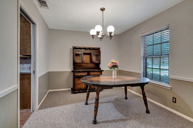 dining room with a textured ceiling, visible vents, a chandelier, and carpet flooring