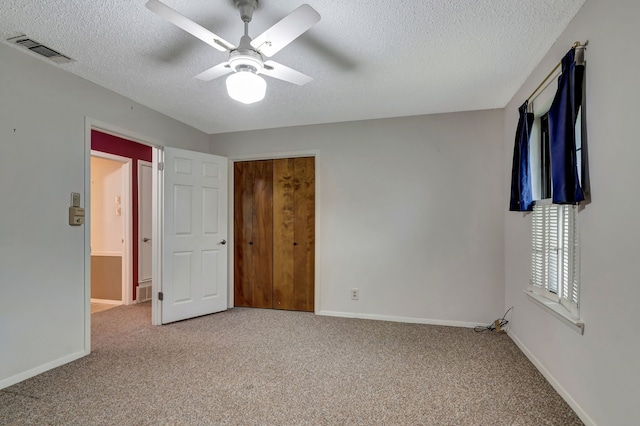 unfurnished bedroom with carpet flooring, a textured ceiling, visible vents, and baseboards