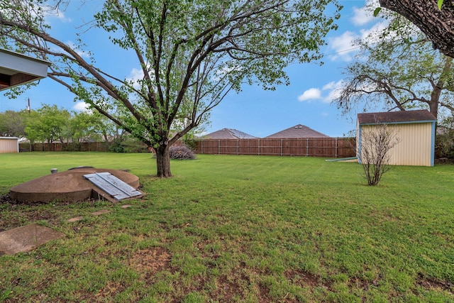 view of yard featuring an outdoor structure, a fenced backyard, and a storage shed