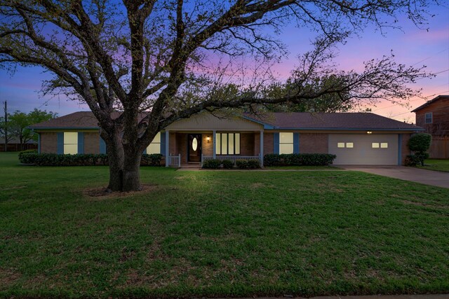 single story home with a lawn, concrete driveway, an attached garage, and brick siding