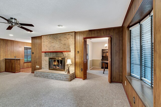 unfurnished living room with a textured ceiling, wooden walls, and ceiling fan
