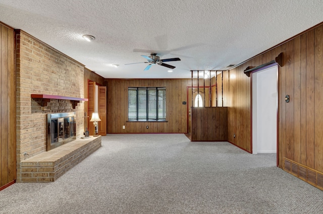 unfurnished living room featuring a fireplace, wooden walls, ceiling fan, and light carpet